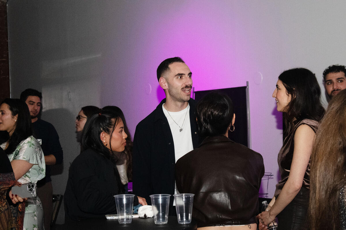 Zaid Fouzi mingling with a group at Habibi In The City, purple backdrop