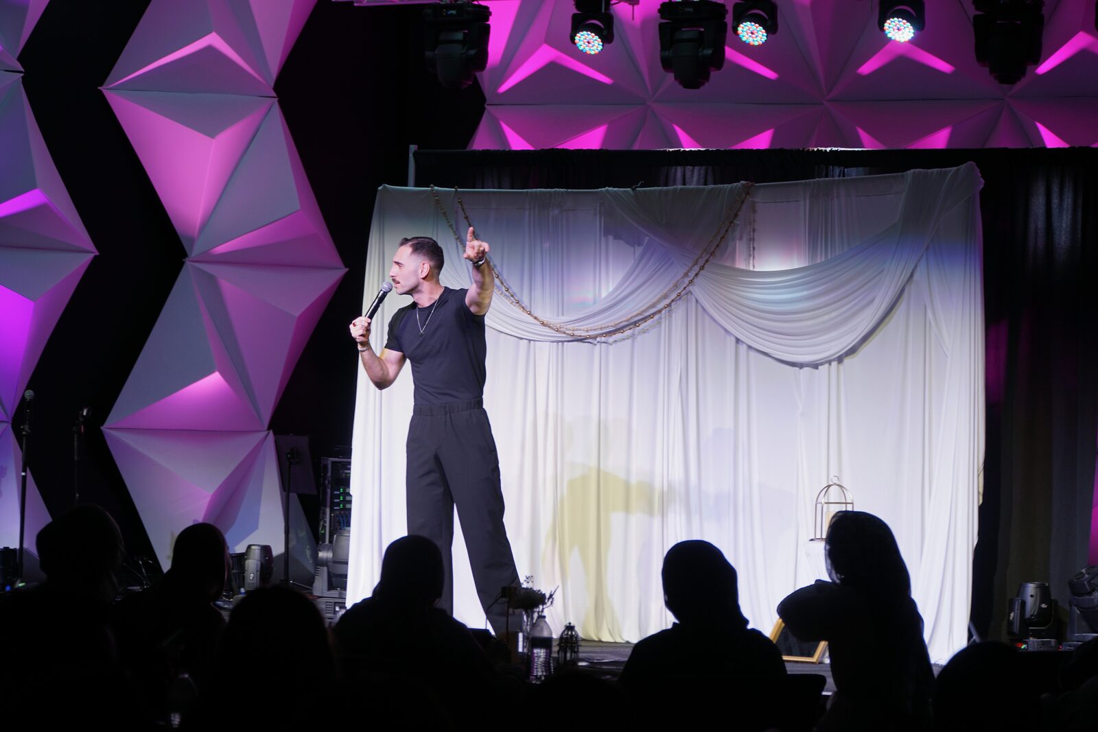 Zaid Fouzi on stage at OU Arab Students Comedy Night, Norman OK, purple geometric backdrop