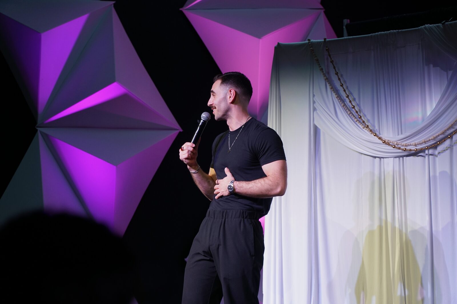 Zaid Fouzi mid-bit at OU Arab Students Comedy Night, Norman OK, hands clasped