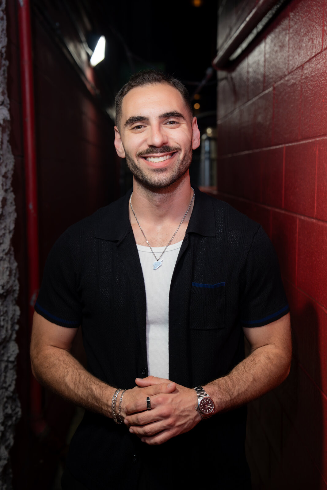 Zaid Fouzi portrait, red wall backstage at Zanies Chicago, big smile