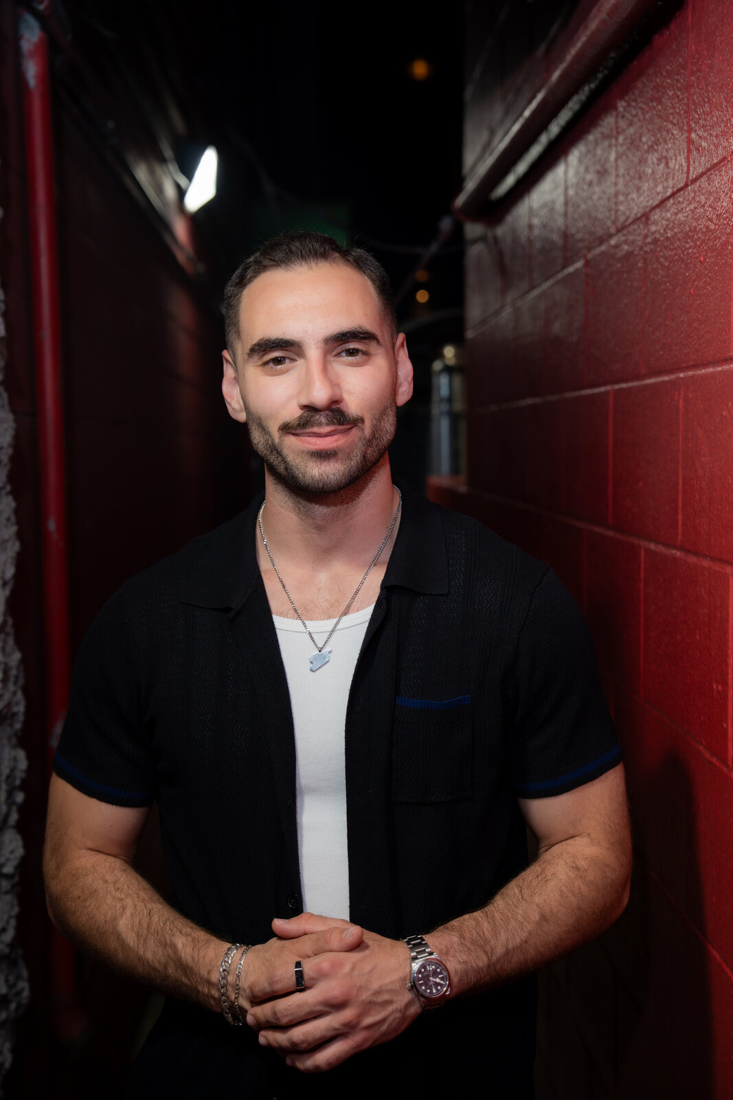 Zaid Fouzi leaning against red wall backstage at Zanies Chicago